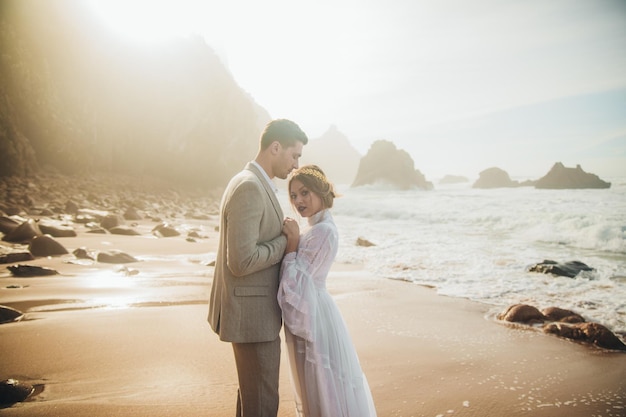 Hermosa pareja de novios de pie entre rocas enamoradas