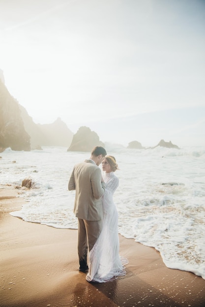 Hermosa pareja de novios de pie entre rocas enamoradas