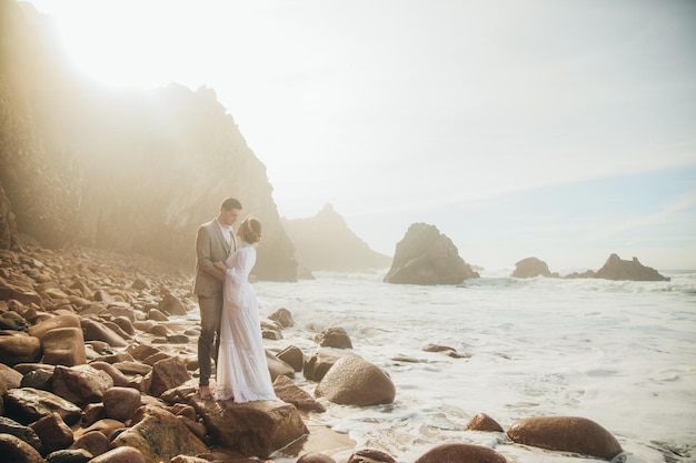 Hermosa pareja de novios de pie entre rocas enamoradas