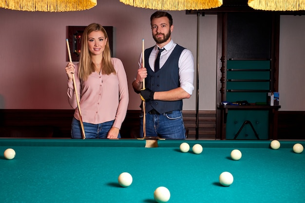 Hermosa pareja pasa un agradable pasatiempo jugando al billar juntos, descanso familiar, entretenimiento, vacaciones