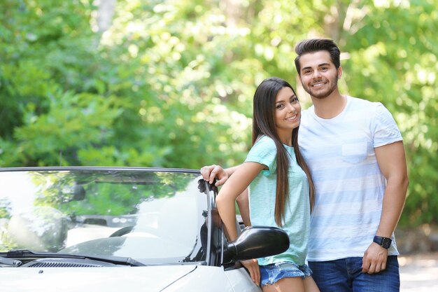 Foto hermosa pareja de pie cerca del coche en la carretera