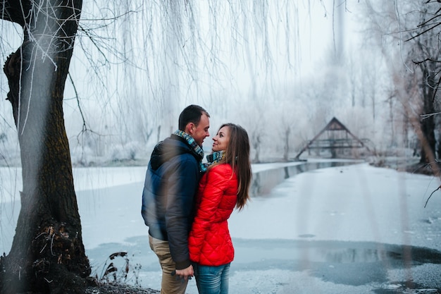 Hermosa pareja posando cerca de un río helado en el parque