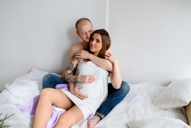 Hermosa pareja en previsión de un niño, acostarse en la cama.