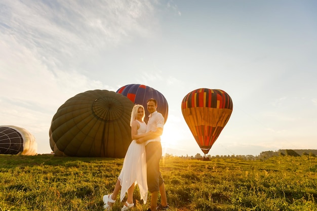 Hermosa pareja romántica abrazándose en la pradera. globo aerostático sobre un fondo