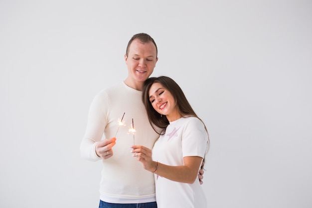 Hermosa pareja romántica teniendo cita en el día de San Valentín hombre y mujer sosteniendo bengalas en blanco