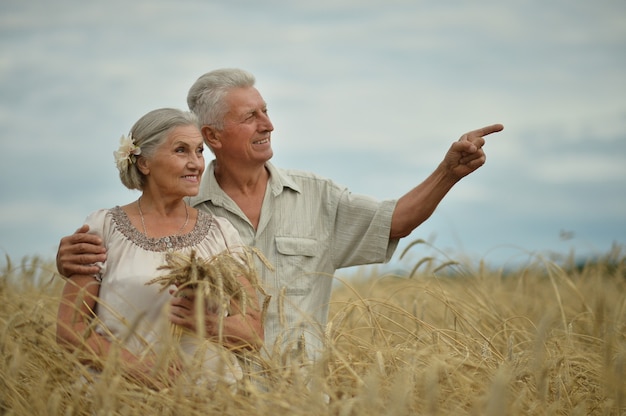 Hermosa pareja senior feliz en campo de verano, hombre apuntando con su mano