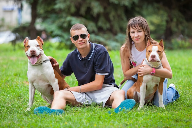 Hermosa pareja sentada en el césped con perros