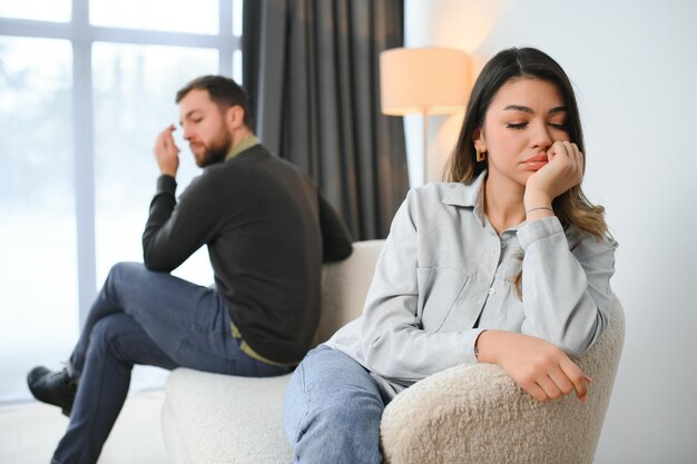 Foto una hermosa pareja está sentada espalda a espalda en el sofá mientras tienen una pelea