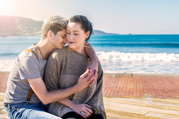 Hermosa pareja sentada junto al mar