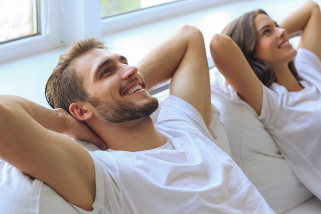 Hermosa pareja sonriente sentada en un sofá y soñando con un nuevo hogar