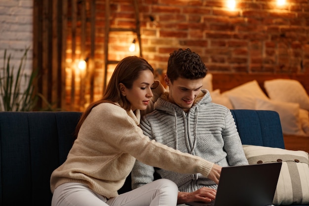 Hermosa pareja sonriente viendo la película de Navidad en casa