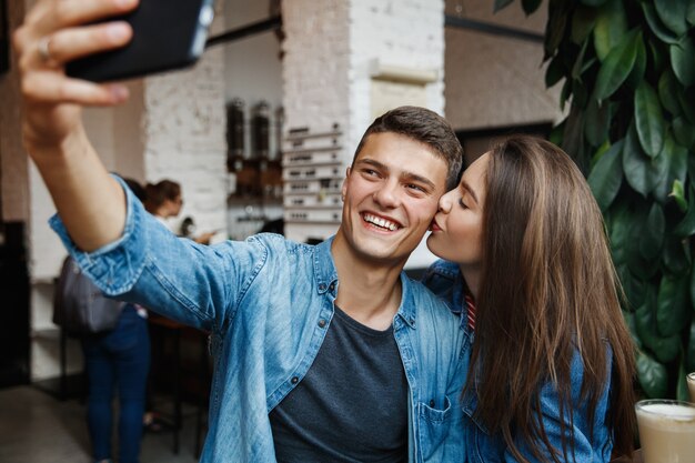 Hermosa pareja tomando fotos en una cafetería