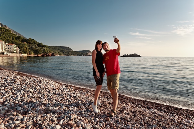 hermosa pareja tomando una selfie junto al mar