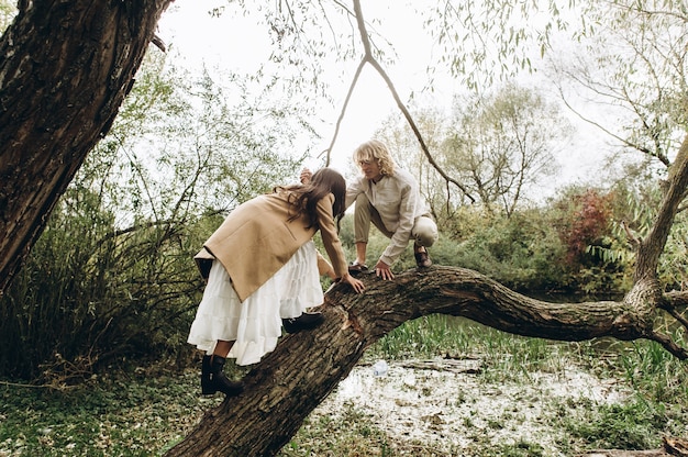 hermosa pareja vestida de estilo boho caminando en el bosque soleado