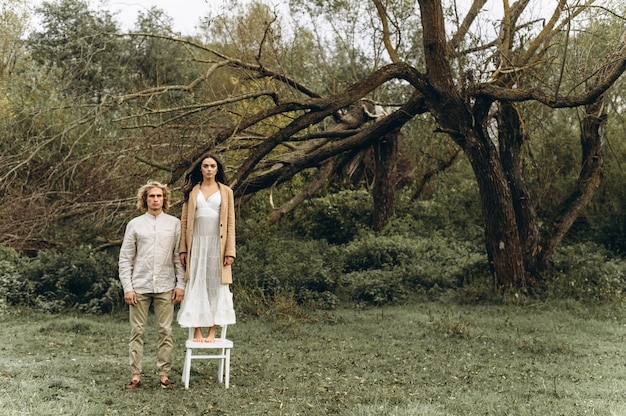 hermosa pareja vestida de estilo boho caminando en el bosque soleado