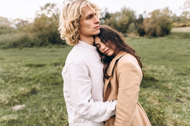 hermosa pareja vestida de estilo boho caminando en el bosque soleado