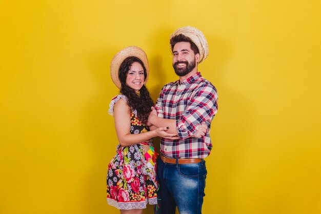 Hermosa pareja vestida con ropa típica para una Festa Junina Arraia de Sao Joao con los brazos cruzados