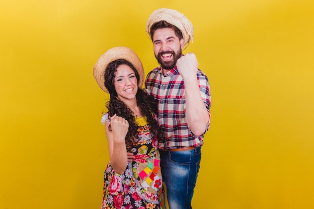 Hermosa pareja vestida con ropa típica para una Festa Junina Arraia de Sao Joao Celebrando la victoria animando