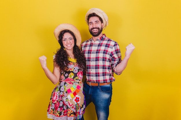 Hermosa pareja vestida con ropa típica para una Festa Junina Arraia de Sao Joao Celebrando la victoria animando