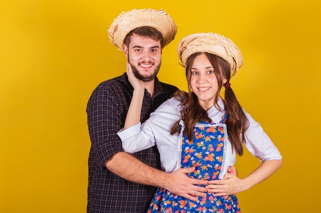 Hermosa pareja vistiendo ropa típica para la Festa Junina abrazando sonriendo