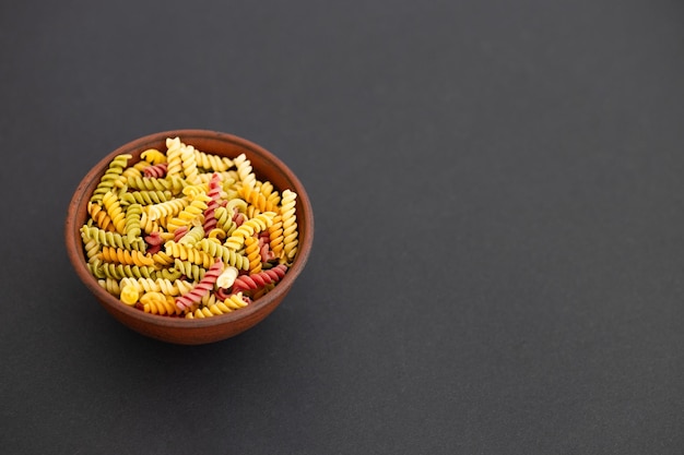 Hermosa pasta italiana de color crudo en un tazón sobre fondo negro