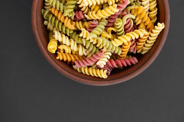 Hermosa pasta italiana de color crudo en un tazón sobre fondo negro