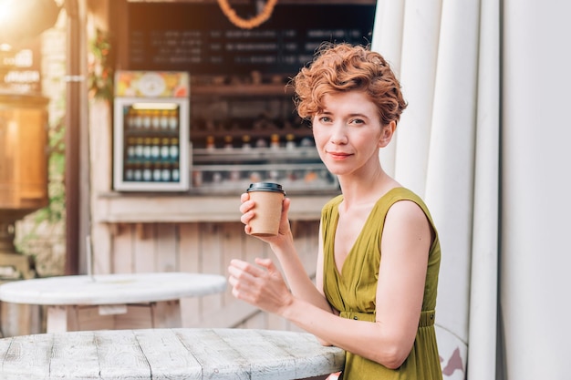 Una hermosa pelirroja con un vestido y una taza de café.