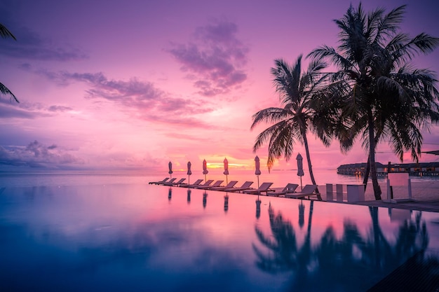 Hermosa piscina y cielo al atardecer. Paisaje de resort de playa tropical de lujo, sillas, camas, palmeras