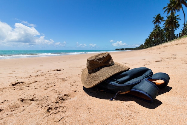 Hermosa playa de agua verde desierta con una mochila y un sombrero en la arena