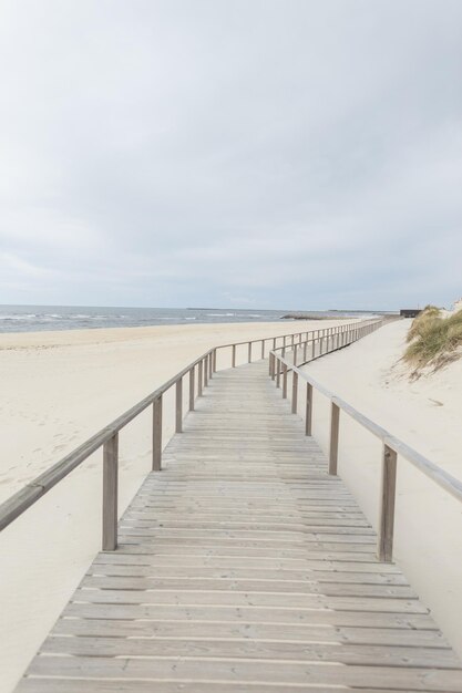 Hermosa playa de arena con una pasarela de madera junto al mar