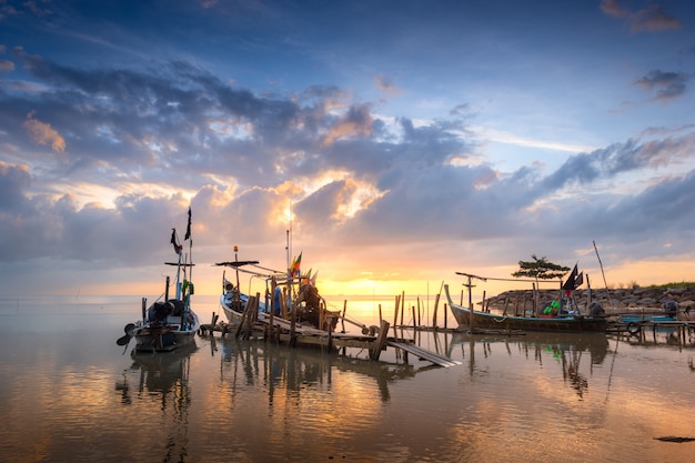 Hermosa playa con barco de pescadores durante el amanecer.