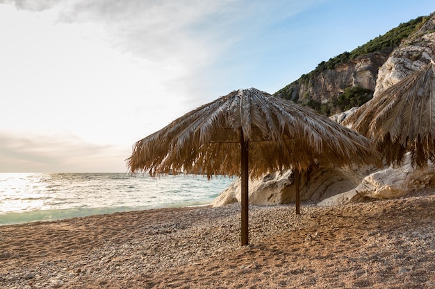 Hermosa playa escénica puesta de sol vista al mar de sombrilla de hojas de palma