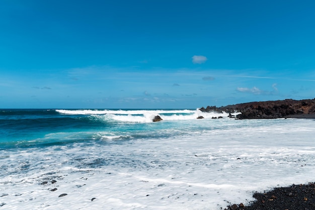 Foto hermosa playa en la isla de lanzarote. playa de arena rodeada de montañas volcánicas / océano atlántico y maravillosa playa. lanzarote. islas canarias