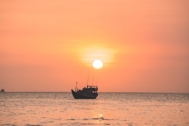 Hermosa playa tropical al atardecer con bote pequeño y cielo rosa para viajes y vacaciones en vacaciones