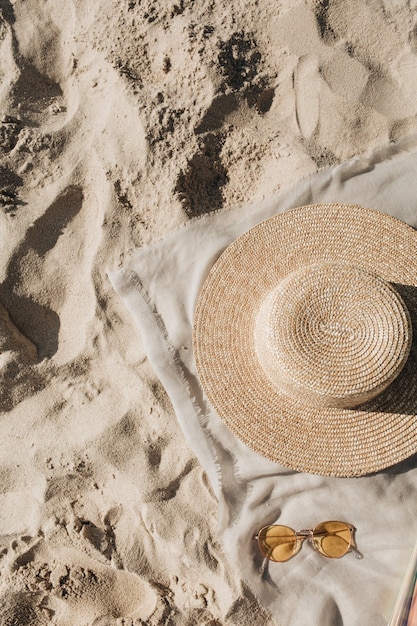 Hermosa playa tropical con arena blanca, escalones, manta neutra con sombrero de paja y gafas de sol
