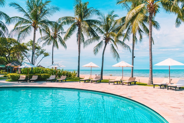 Hermosa playa tropical y mar con sombrilla y silla alrededor de la piscina en el complejo hotelero