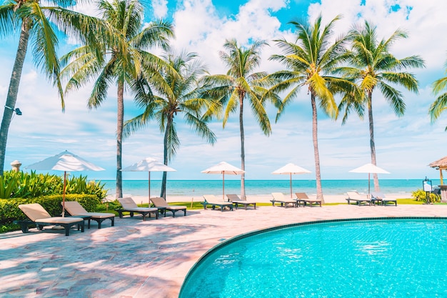 Hermosa playa tropical y mar con sombrilla y silla alrededor de la piscina en el hotel resort para viajes y vacaciones