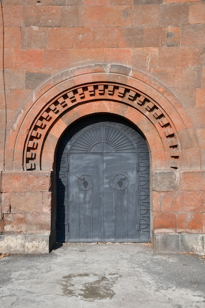 Hermosa puerta de metal en un muro de piedra. El arco de la puerta es de piedra.