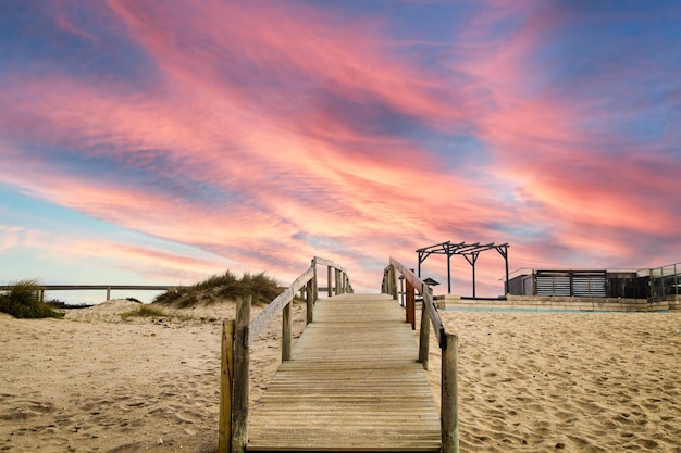 Una hermosa puesta de sol, con un camino de madera en la playa de Furadouro en Portugal.