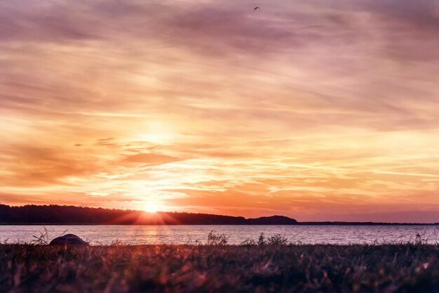 Hermosa puesta de sol con cielo rojo amarillo en el resplandor en la playa junto al mar