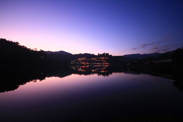 Hermosa puesta de sol y crepúsculo de la reflexión del cielo sobre la superficie del agua y el lago en la aldea de la tribu hill en tailandia