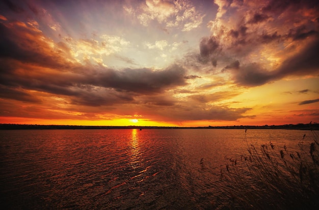 Una hermosa puesta de sol inquietante sobre el agua de un lago o río