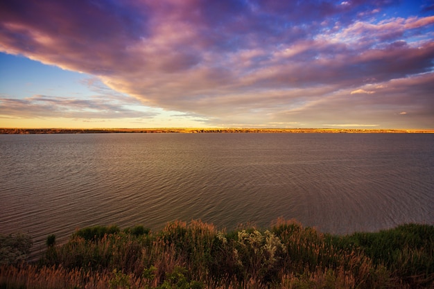 Hermosa puesta de sol en el lago con nubes y reflejos en el agua