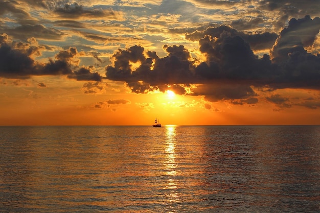 Hermosa puesta de sol en el mar. Un yate es visible en la distancia.