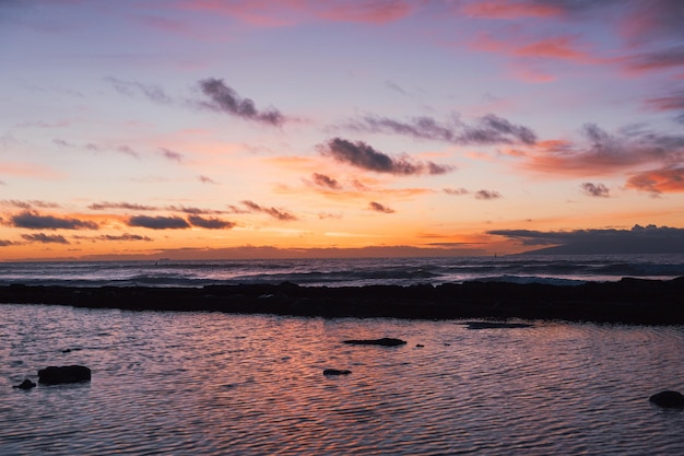 Hermosa puesta de sol en la playa con el cielo colorido y el reflejo en el agua