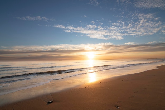 Una hermosa puesta de sol en la playa de Mazagón España En el fondo las siluetas de dos surfistas