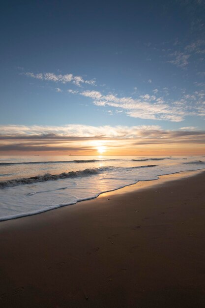 Una hermosa puesta de sol en la playa de Mazagón España En el fondo las siluetas de dos surfistas