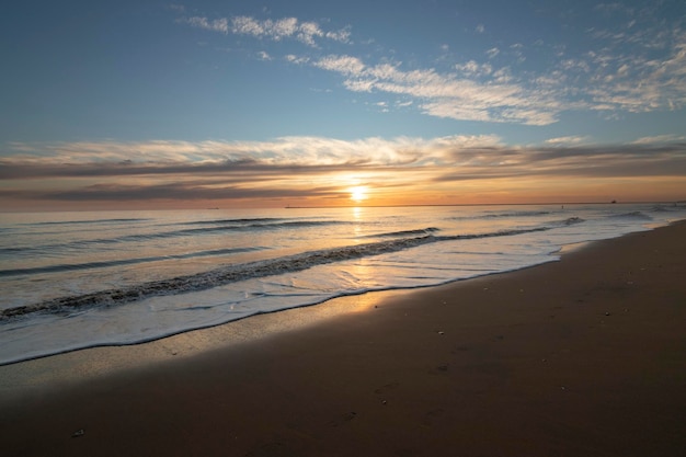 Una hermosa puesta de sol en la playa de Mazagón España En el fondo las siluetas de dos surfistas