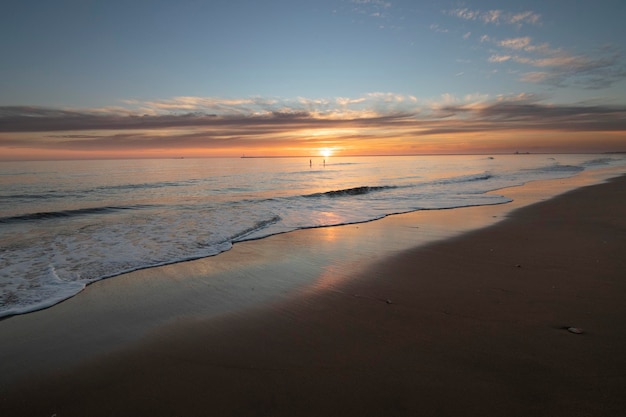 Una hermosa puesta de sol en la playa de Mazagón España En el fondo las siluetas de dos surfistas