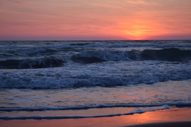 Foto una hermosa puesta de sol en la playa en el océano turbulento